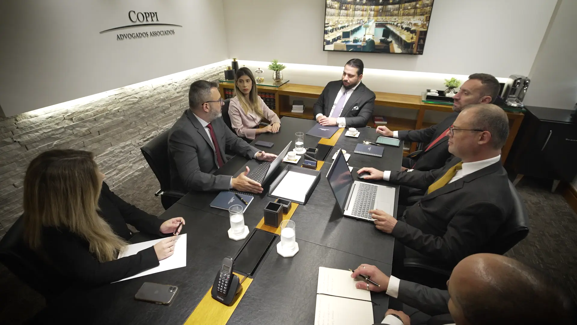 Reunião de equipe em torno da mesa na sala do escritório Coppi Advogados