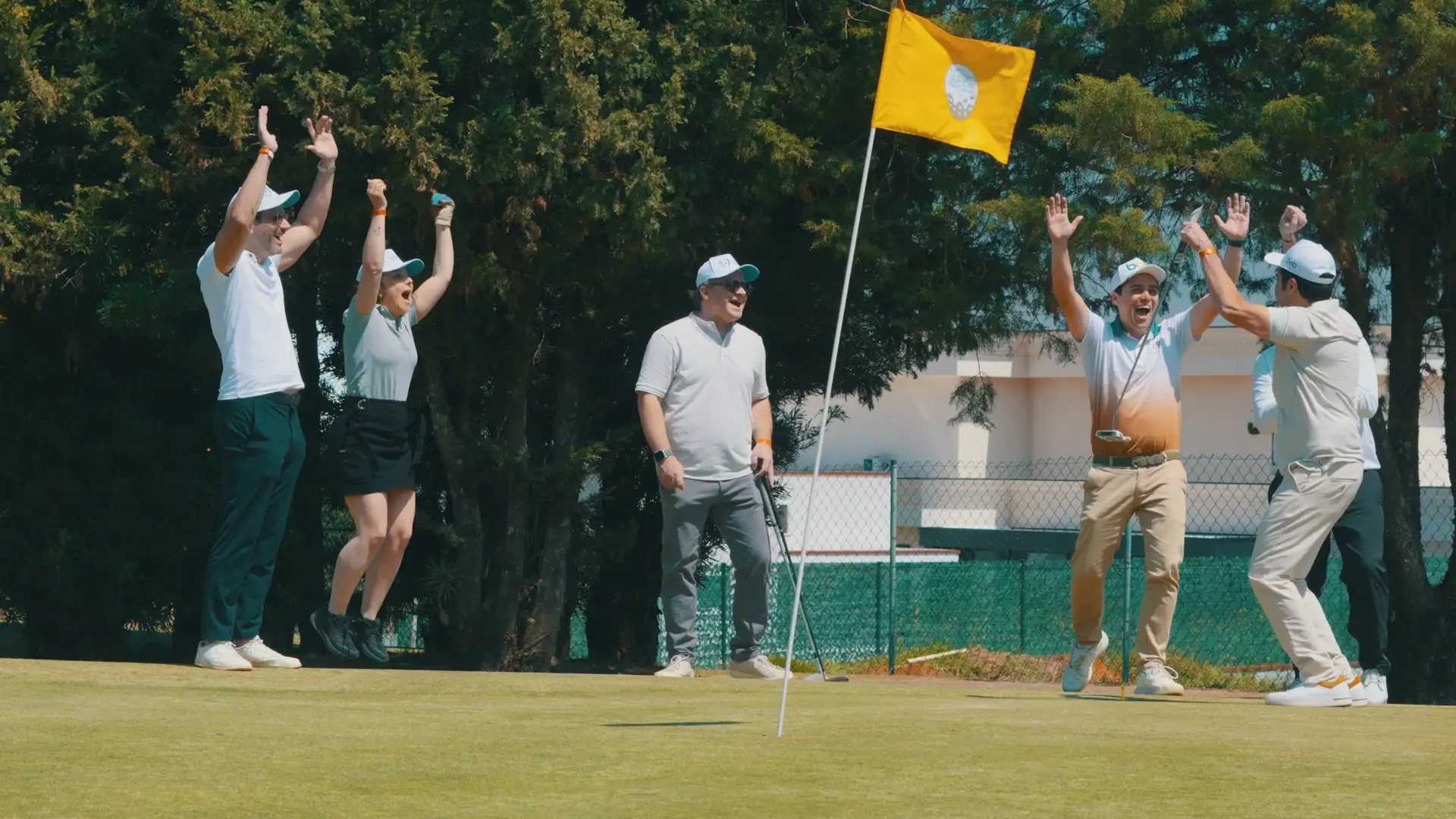 Grupo reunido no green de golfe ao lado da bandeira, em contraluz